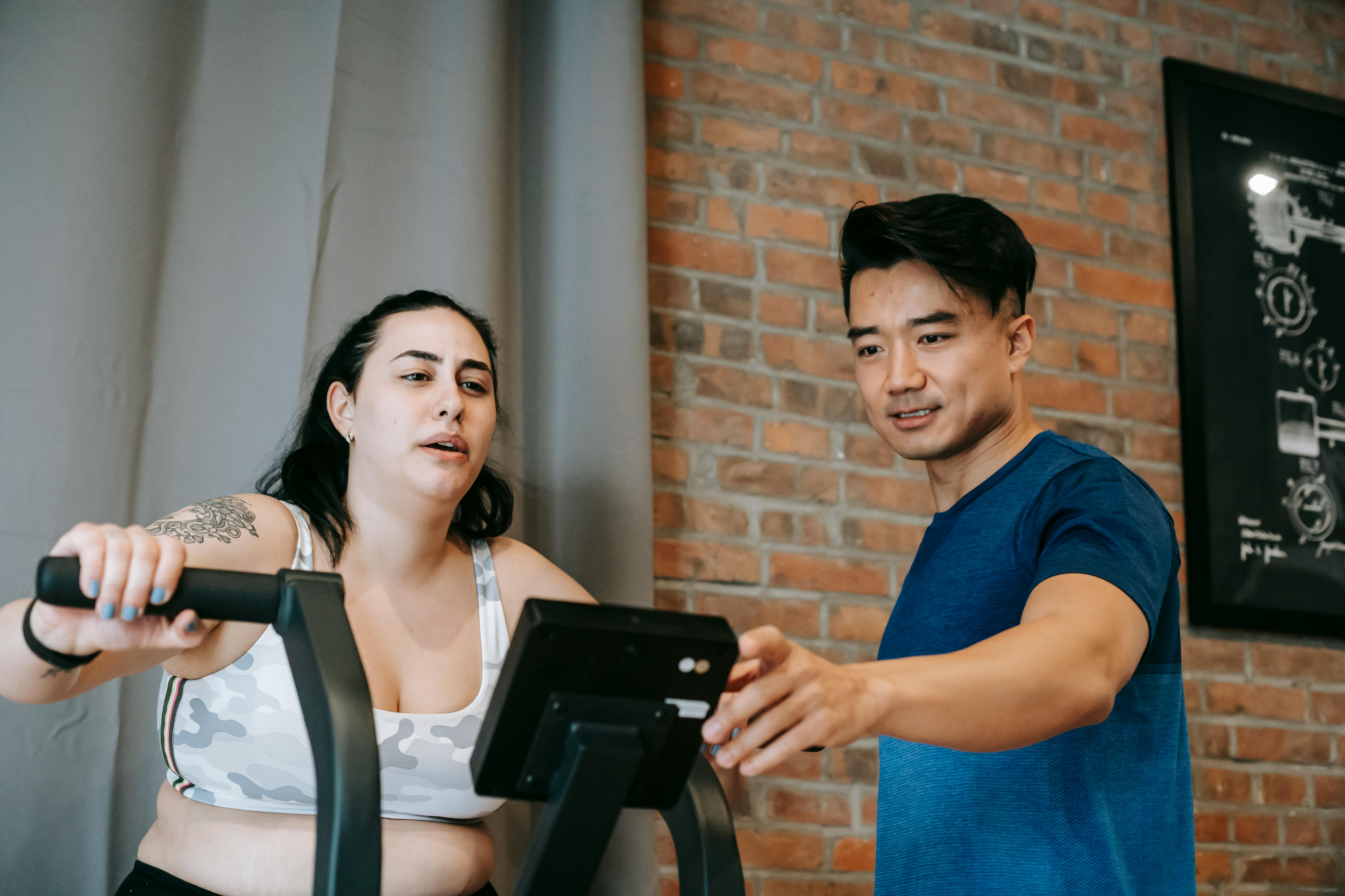 Fitness coach guiding a client during an indoor cycling assessment session.
